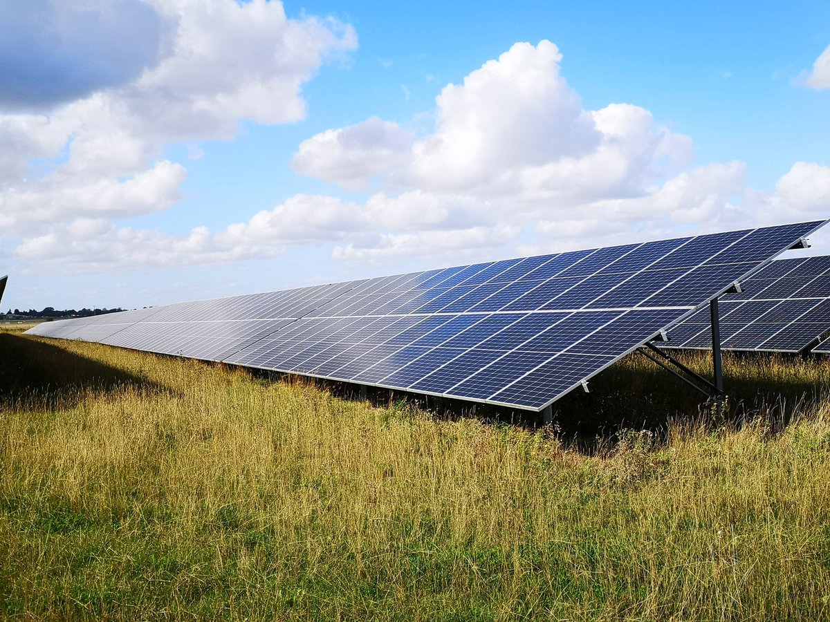 Solar panels in the countryside with blue sky and clouds, representing clean renewable energy