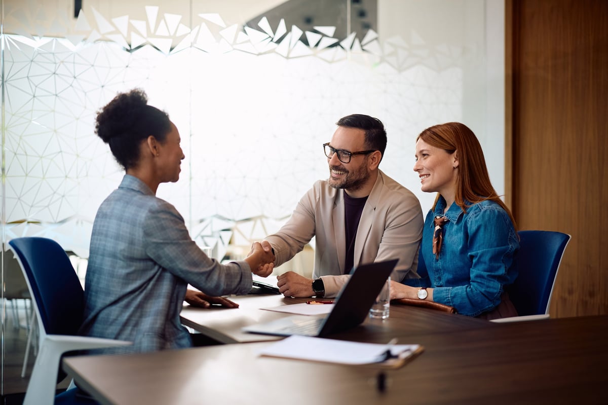 Couple shaking hands with advisor for solar financing agreement in office