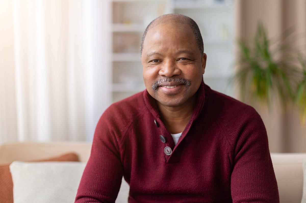 Cheerful mature man customer sitting at home smiling at camera